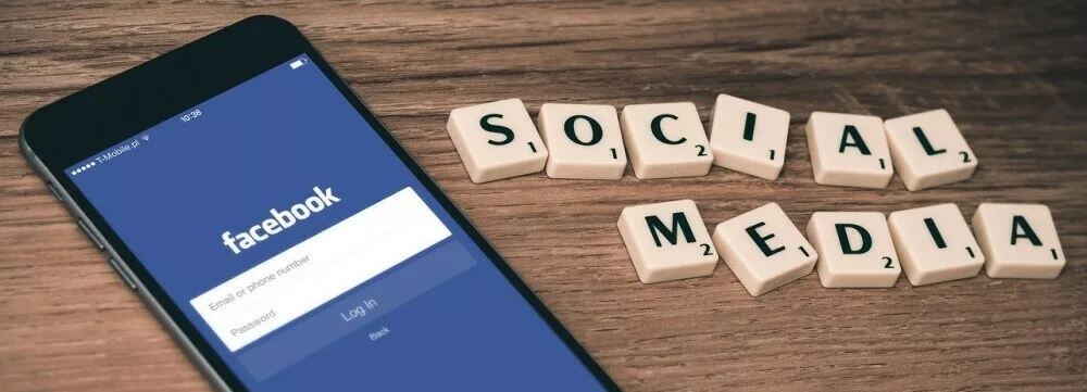 social media spelt in scrabble tiles plus a mobil with the facebook login screen